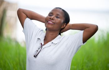 A relaxed Afro-American woman in a park breathing deeply.