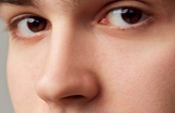 Looking in camera. Close-up portrait of young man with brown eyes. Eyes, nose. Vision care. Concept of men's health, body and skin care, hygiene and male cosmetology