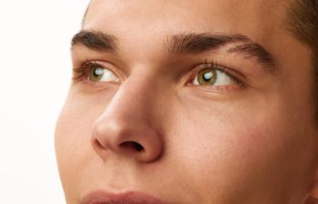Close-up cropped image of male face, eyes, nose and eyebrows against white studio background. Concept of male beauty, skin care, spa, cosmetology, men's health