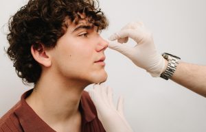 Rhinoplasty surgery preparation for man. ENT is touching nose and consulting man. Final examination before septoplasty surgery